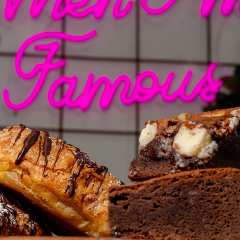 Plated chocolate croissant and slice under the Mother Milk Famous pink neon sign