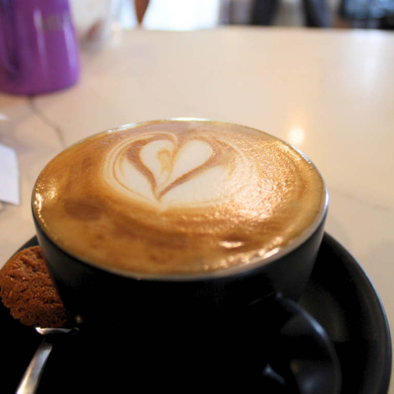 Cappuccino with heart latte art and biscotti on the side